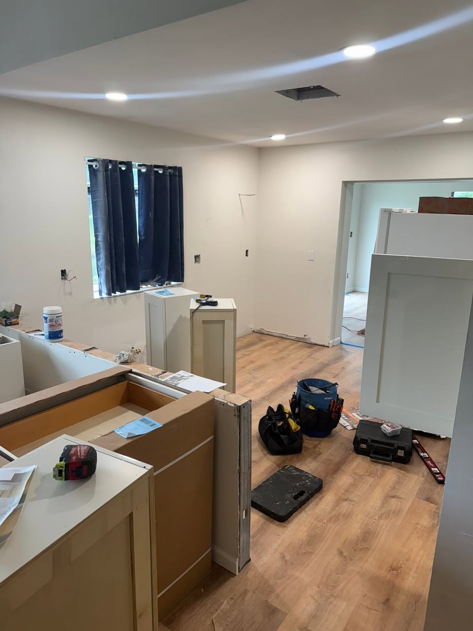 Kitchen cabinetry during installation with cabinet doors removed and tools on the counters